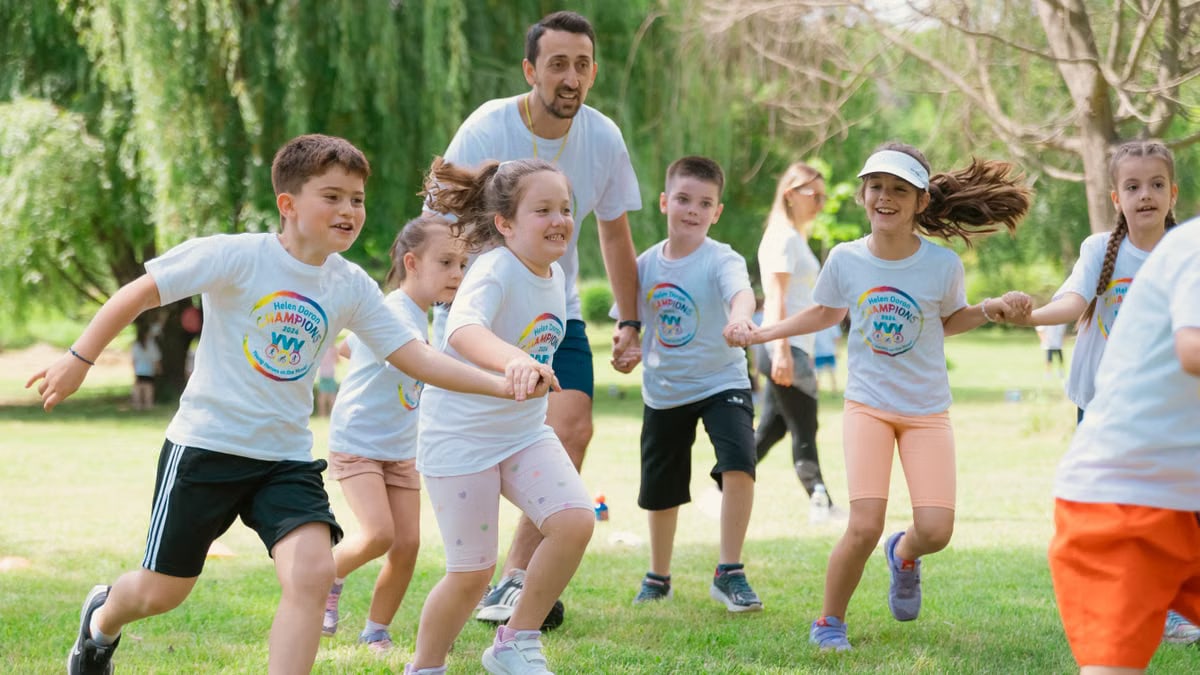 Children joyfully running and holding hands in a sunny park, enjoying outdoor recreation.